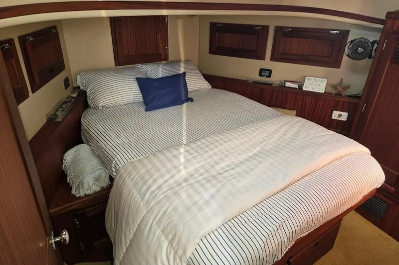 Slide: The Image of Cozy bedroom in 2010 American Tug "34" Pilothouse Trawler with striped bedding and wooden accents. - 10