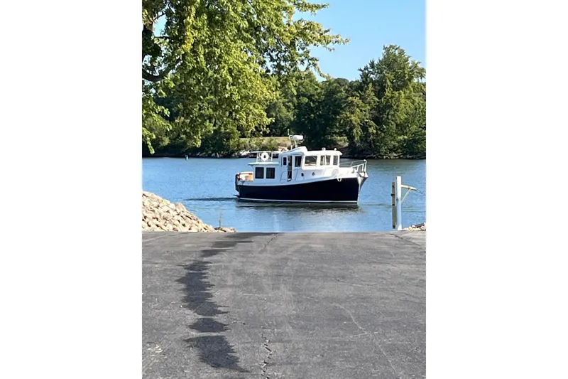 Slide: The Image of 2010 American Tug "34" Pilothouse Trawler on a serene lake with lush greenery. - 117
