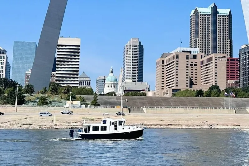 Slide: The Image of American Tug "34" Pilothouse Trawler cruising near city skyline and iconic arch. - 119