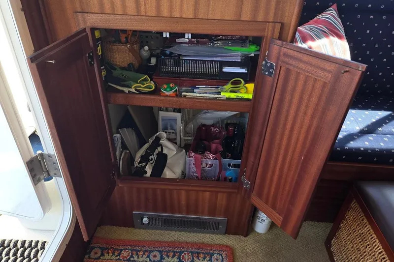 Slide: The Image of Open wooden cabinet in 2010 American Tug "34" Pilothouse Trawler, revealing organized storage. - 34