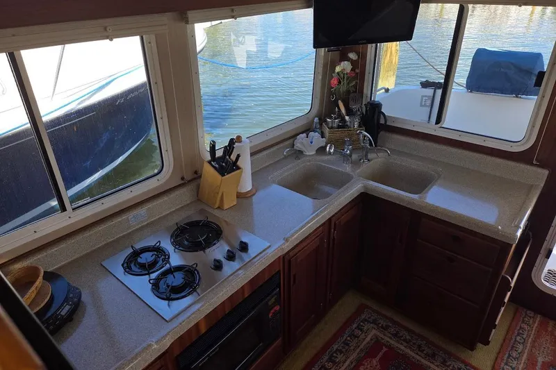 Slide: The Image of 2010 American Tug 34 Pilothouse Trawler kitchen with stove, sink, and windows overlooking water. - 35