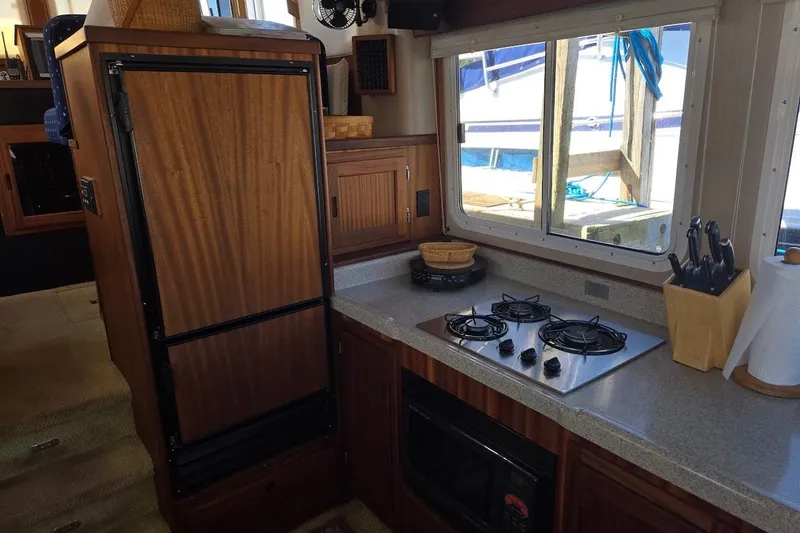 Slide: The Image of 2010 American Tug "34" Pilothouse Trawler kitchen with stove, fridge, and window view. - 37