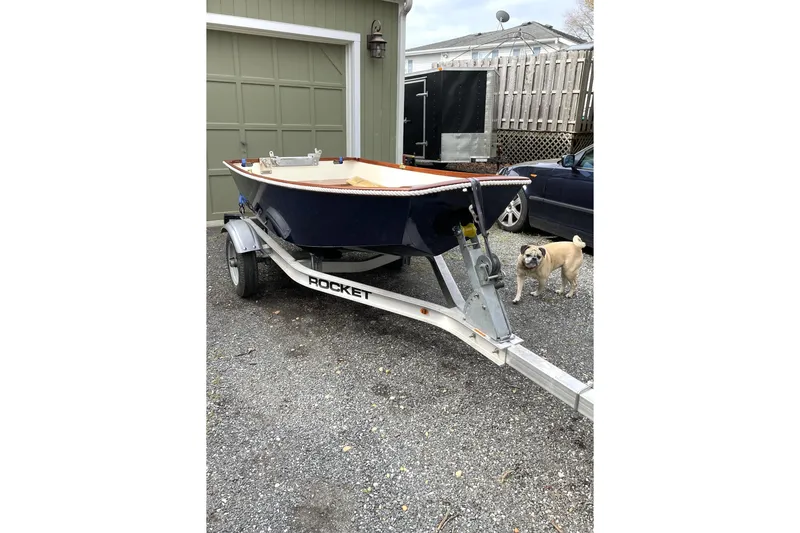Slide: The Image of 2010 American Tug "34" Pilothouse Trawler on trailer, parked near garage with a dog nearby. - 99