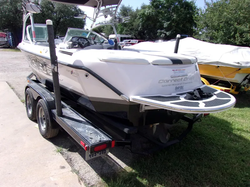 Slide: The Image of 2006 Correct Craft SUPER AIR NAUTIQUE 210 TEAM EDITION boat on trailer, parked outdoors. - 4