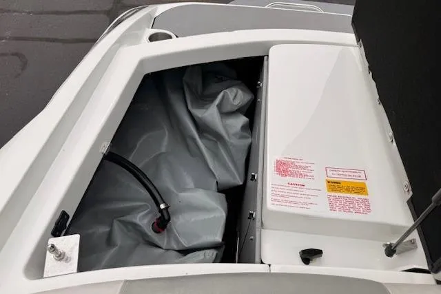 Slide: The Image of 2013 Centurion Enzo SV244 boat storage compartment with safety labels and hose. - 22