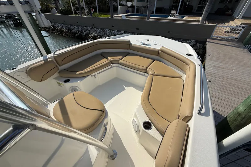 Slide: The Image of 2018 NauticStar 211 Coastal boat with tan cushioned seating in a marina setting. - 15