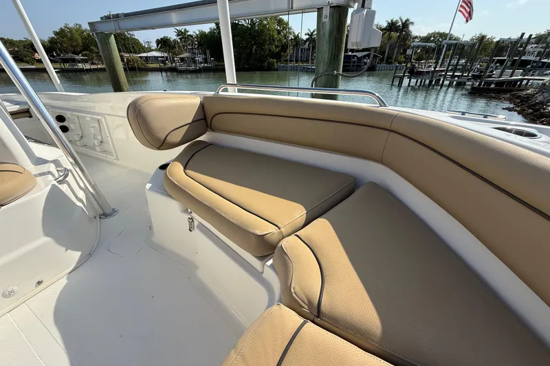 Slide: The Image of 2018 NauticStar 211 Coastal boat interior with tan seating, docked by a serene waterfront. - 18