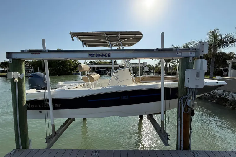 Slide: The Image of 2018 NauticStar 211 Coastal boat on lift, docked by palm trees and calm water. - 3