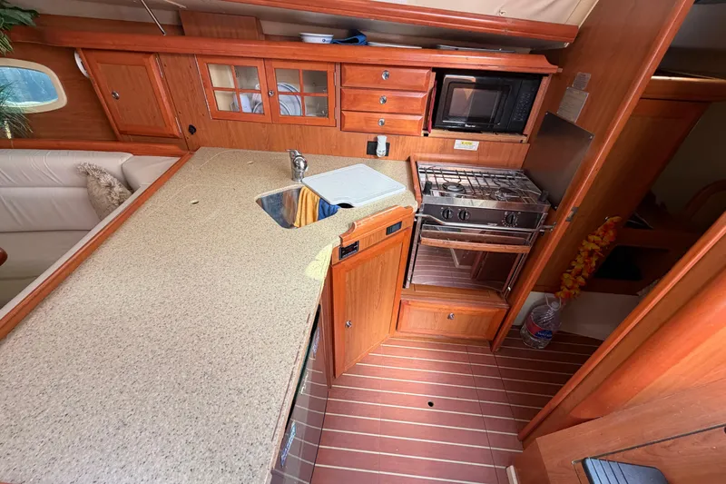Slide: The Image of 2008 Hunter 36 yacht interior kitchen with wooden cabinetry, stove, and sink. - 15