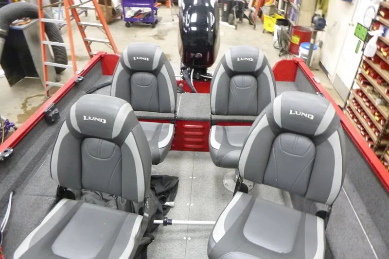 Slide: The Image of 2022 Lund 1650 Angler Sport boat interior with four gray seats in a workshop. - 11