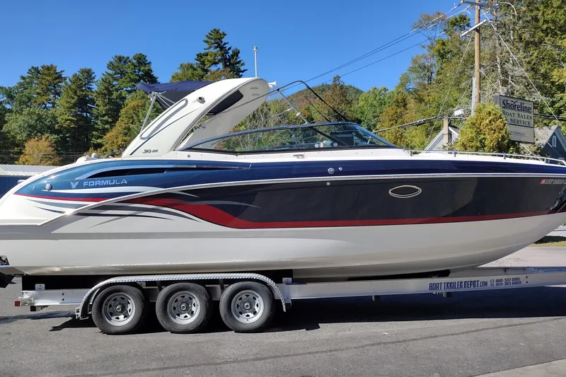 Slide: The Image of 2022 Formula 310 Bowrider boat on trailer, parked outdoors with trees in background. - 0