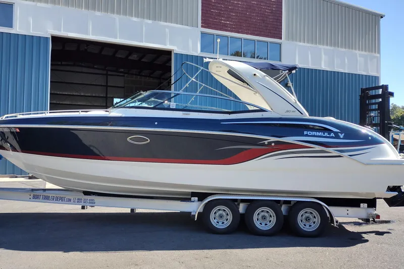 Slide: The Image of 2022 Formula 310 Bowrider boat on trailer outside a large warehouse. - 1