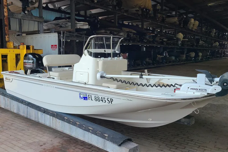 Slide: The Image of 2019 Boston Whaler 150 Montauk boat in storage, featuring Mercury and Minn Kota motors. - 1