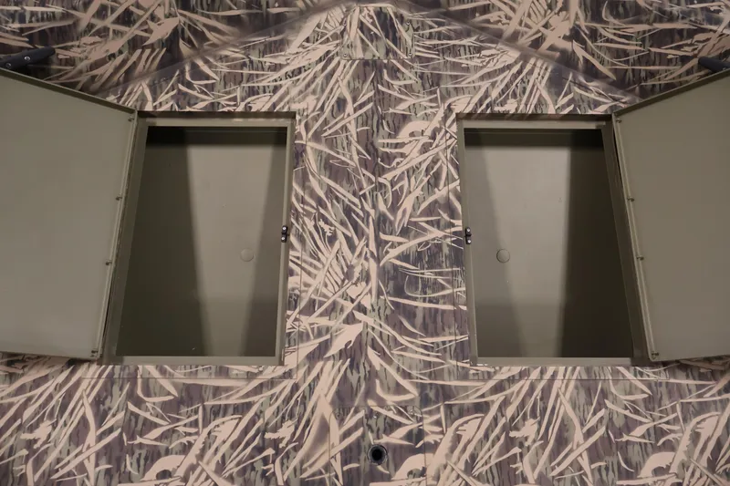 Slide: The Image of 2024 Crestliner 1870 Retriever FCC boat with open storage compartments and camouflage design. - 13