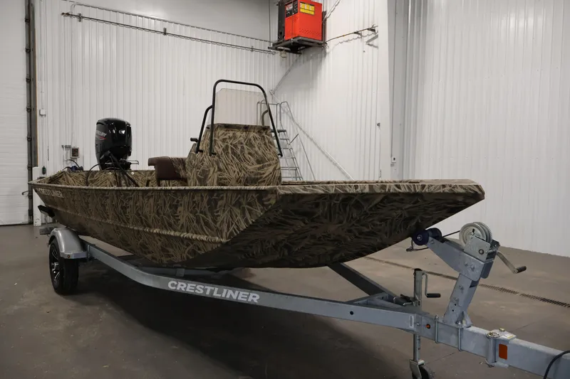 Slide: The Image of 2024 Crestliner 1870 Retriever FCC boat with camouflage design on a trailer in a garage. - 3