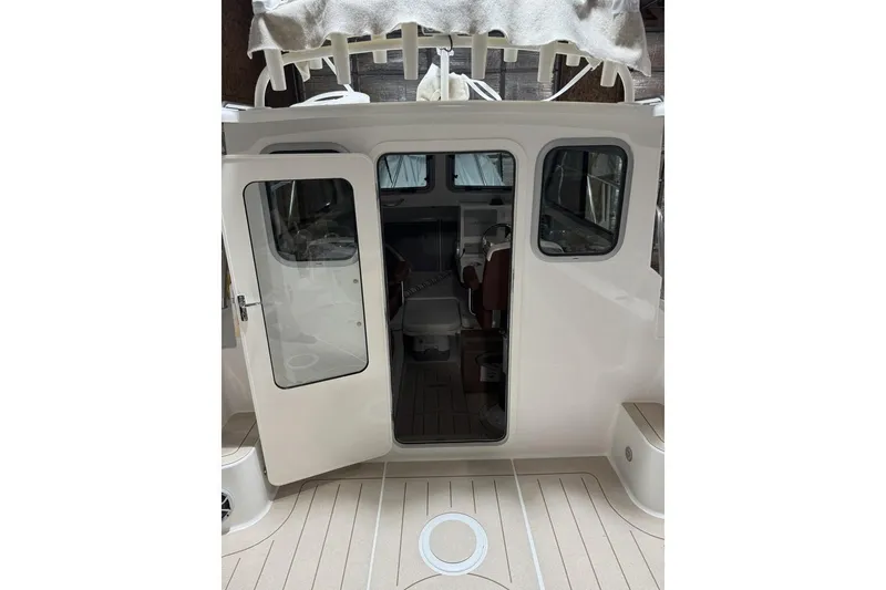 Slide: The Image of 2025 Parker 2420 Sport Cabin boat interior with open door, showcasing seating and helm. - 15