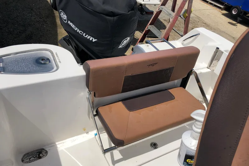 Slide: The Image of 2018 Tidewater 210 CC Adventure boat interior with brown seating and Mercury engine cover. - 2
