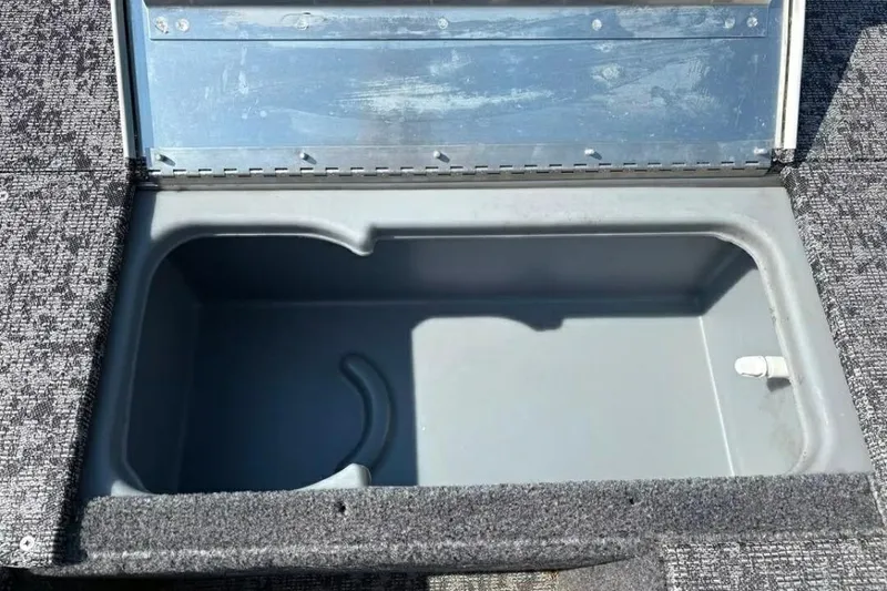 Slide: The Image of Open storage compartment in 2025 Tracker Pro 170 boat, featuring gray interior and carpeted edges. - 11