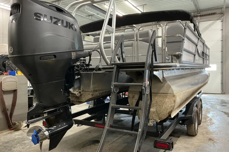 Slide: The Image of 2025 Bentley Pontoons Legacy 240 Swingback with Suzuki outboard motor in a garage setting. - 5