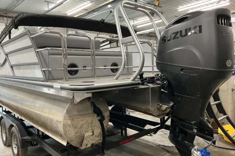Slide: The Image of 2025 Bentley Pontoons Legacy 240 Swingback with Suzuki outboard motor in a garage. - 6