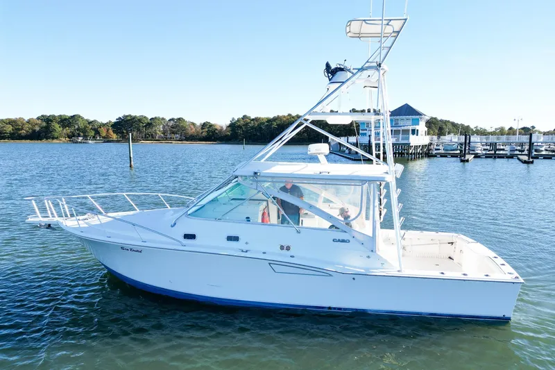 Slide: The Image of 1996 Cabo 35 Express boat on calm water near a marina. - 2
