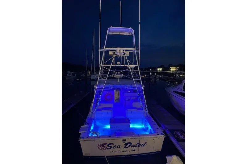 Slide: The Image of 1996 Cabo 35 Express boat with blue deck lights at night in a marina. - 6