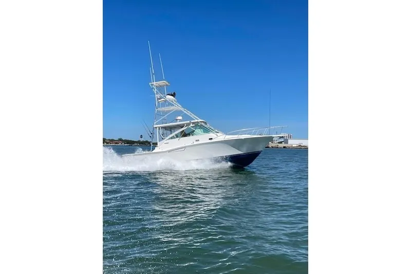 Slide: The Image of 1996 Cabo 35 Express yacht cruising on open water under clear blue sky. - 7