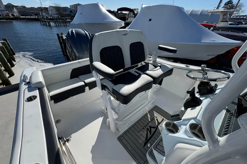 Slide: The Image of 2025 Tidewater 220 LXF boat interior with dual seats and steering wheel at dock. - 10