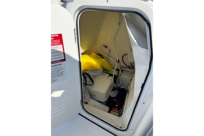 Slide: The Image of Storage compartment inside 2025 Tidewater 220 LXF boat, featuring safety equipment and wiring. - 13
