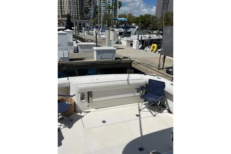 Slide: The Image of 2002 Tiara Yachts 4300 Open at marina, featuring spacious deck with chairs. - 5