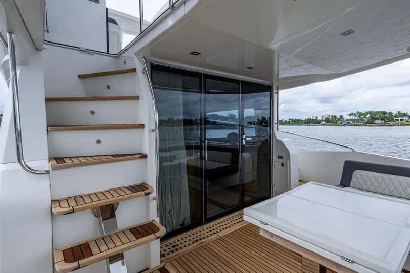 Slide: The Image of 2020 Galeon 550 Fly yacht interior with wooden stairs and glass doors, overlooking water. - 13