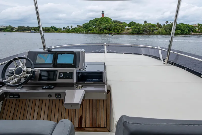 Slide: The Image of 2020 Galeon 550 Fly yacht helm with dual screens, overlooking serene waters and lush greenery. - 15