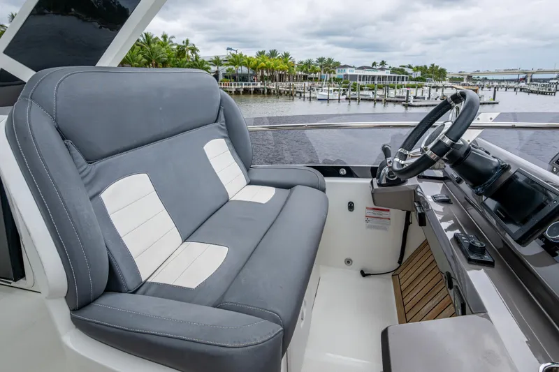 Slide: The Image of Captain's seat and helm of 2020 Galeon 550 Fly yacht, overlooking marina. - 16