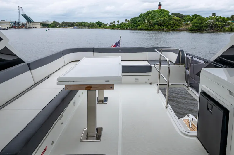 Slide: The Image of 2020 Galeon 550 Fly yacht deck with seating and table, overlooking scenic waterfront. - 18