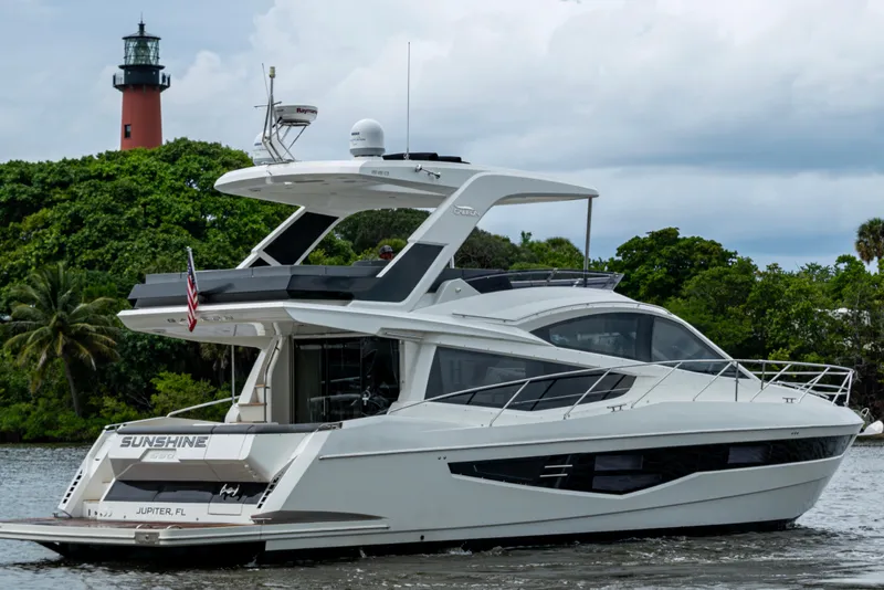 Slide: The Image of 2020 Galeon 550 Fly yacht cruising near a lighthouse and lush greenery. - 52
