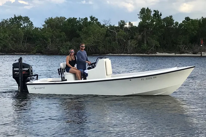 The Image of 1973 Aquasport 190 Osprey boat on water with two people aboard, surrounded by trees. - 1