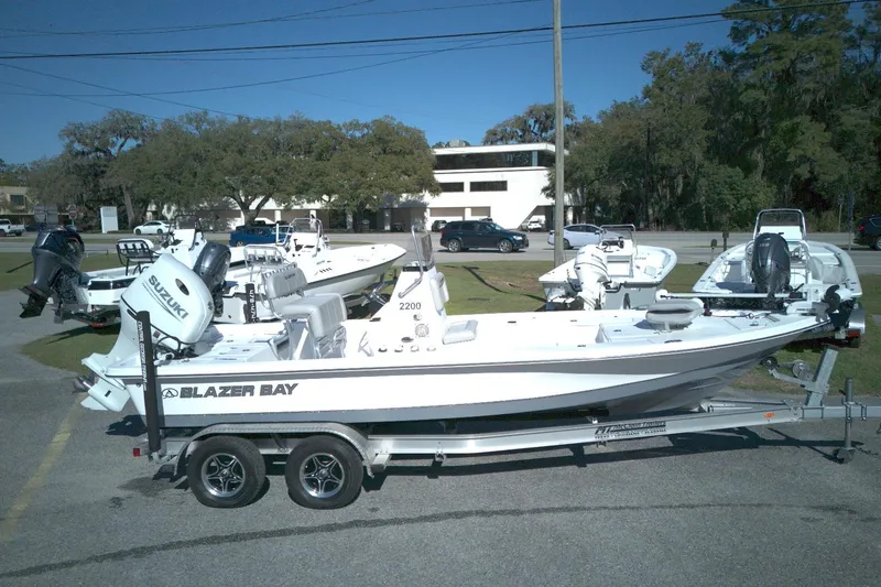 The Image of 2022 Blazer Bay 2200 boat on trailer, parked outdoors with other boats nearby. - 0