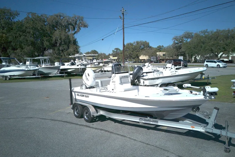 Slide: The Image of 2022 Blazer Bay 2200 boat on trailer in outdoor showroom with other boats. - 1