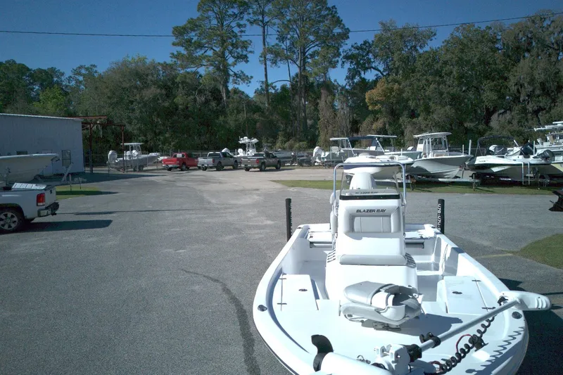 Slide: The Image of 2022 Blazer Bay 2200 boat parked outdoors in a marina with surrounding trees. - 2