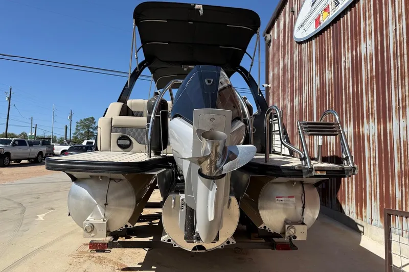 Slide: The Image of 2022 Barletta L23UCA pontoon boat with outboard motor and ladder, parked outdoors. - 3
