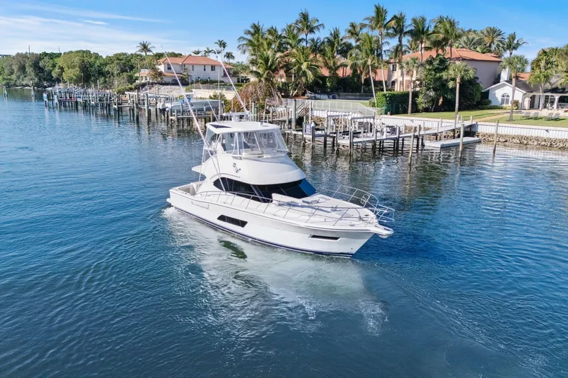 Slide: The Image of 2016 Riviera 43 Open Flybridge yacht cruising near waterfront homes and palm trees. - 10