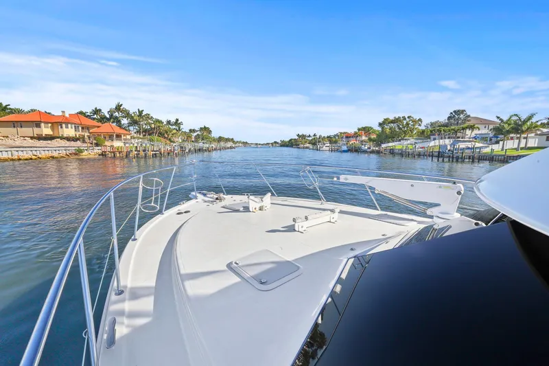 Slide: The Image of 2016 Riviera 43 Open Flybridge cruising through a scenic waterfront neighborhood. - 14