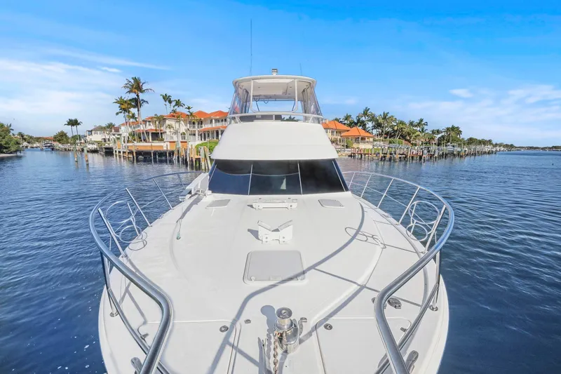 Slide: The Image of 2016 Riviera 43 Open Flybridge yacht cruising near waterfront homes and palm trees. - 18