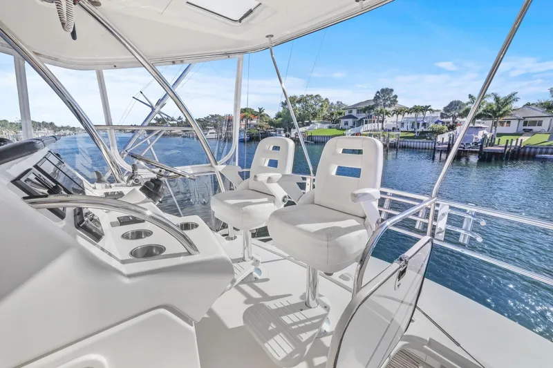Slide: The Image of Flybridge of 2016 Riviera 43 Open, featuring helm chairs and waterfront view. - 19