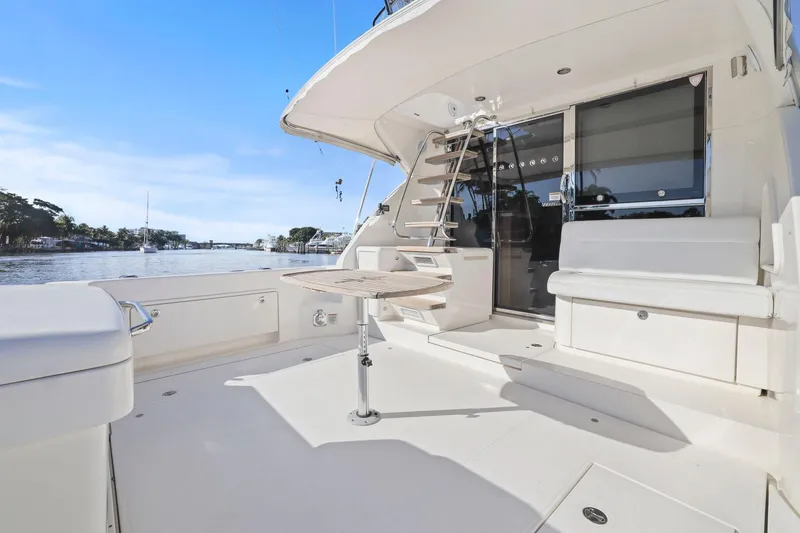 Slide: The Image of 2016 Riviera 43 Open Flybridge yacht deck with seating and table, overlooking serene waters. - 26