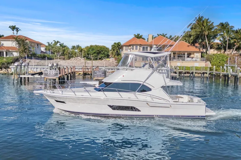 Slide: The Image of 2016 Riviera 43 Open Flybridge yacht cruising near waterfront homes. - 7