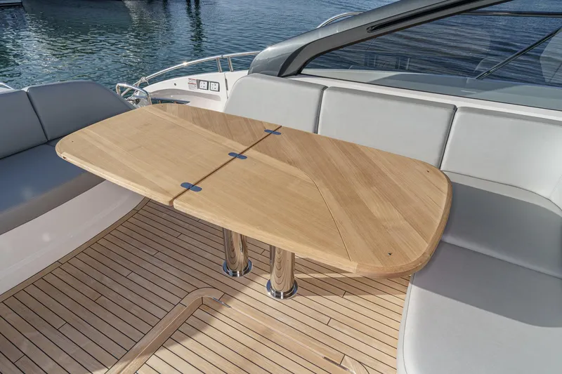Slide: The Image of Luxury seating area on 2026 Princess V55 yacht with wooden table and cushioned seats. - 12