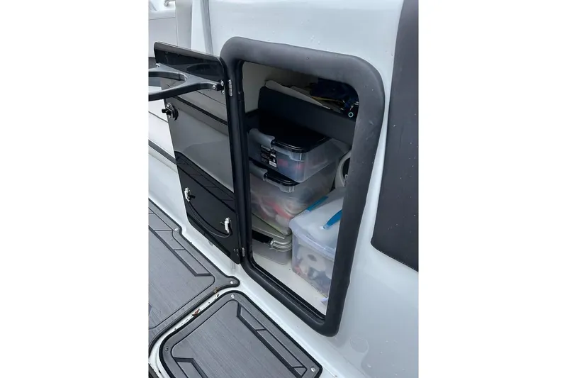 Slide: The Image of Storage compartment on a 2019 Rinker Q3 OB boat, containing organized plastic containers. - 13