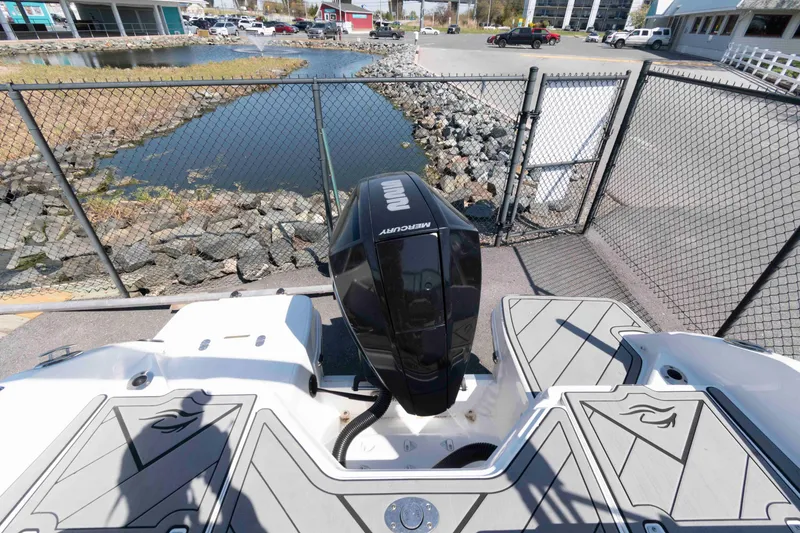 Slide: The Image of 2019 Rinker Q3 OB boat with Mercury outboard motor, docked near a fenced waterfront area. - 15