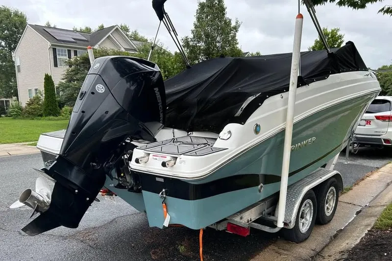 Slide: The Image of 2019 Rinker Q3 OB boat on trailer with cover, parked in residential area. - 2